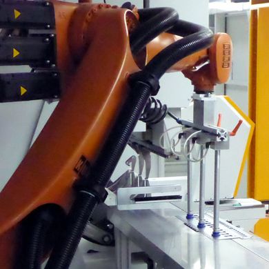 Der Roboter übergibt die Platine dem MiniBendCenter am Saugertisch